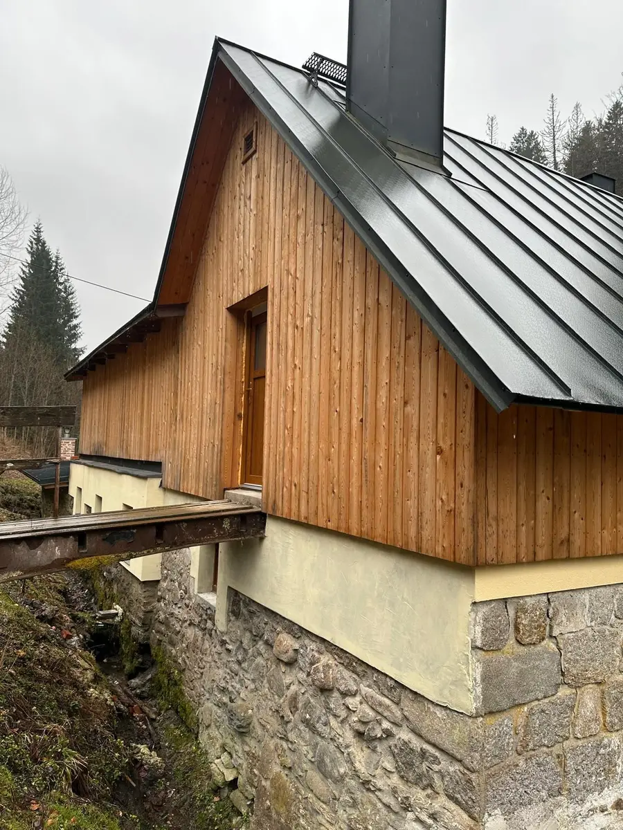 Nové vchodové dveře v šedé omítkové špaletě na fasádě dokončeného domu